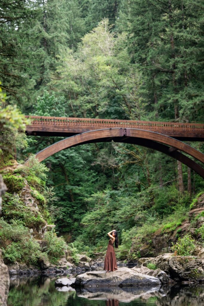 high school senior long brown dress on river rock with bridge