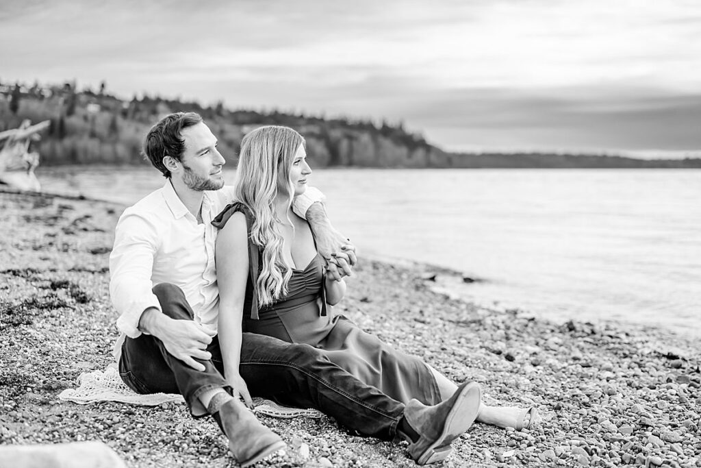 seated pose engaged couple rocky beach