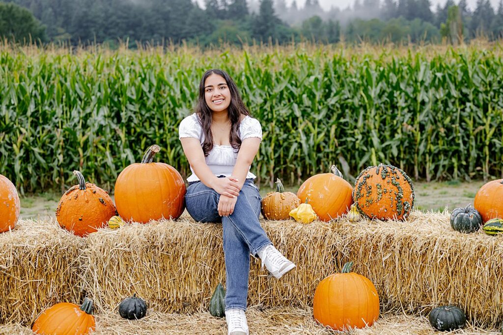 hay bales senior portrait pose with pumpkins and corn maze