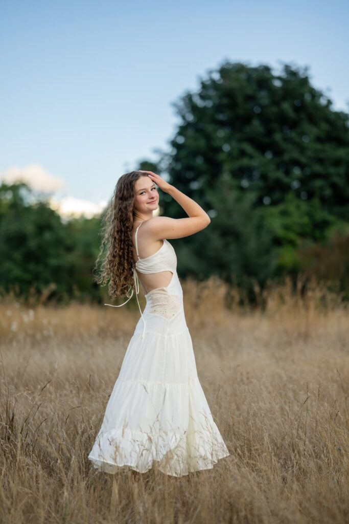 high school senior girl in an open field with long white dress