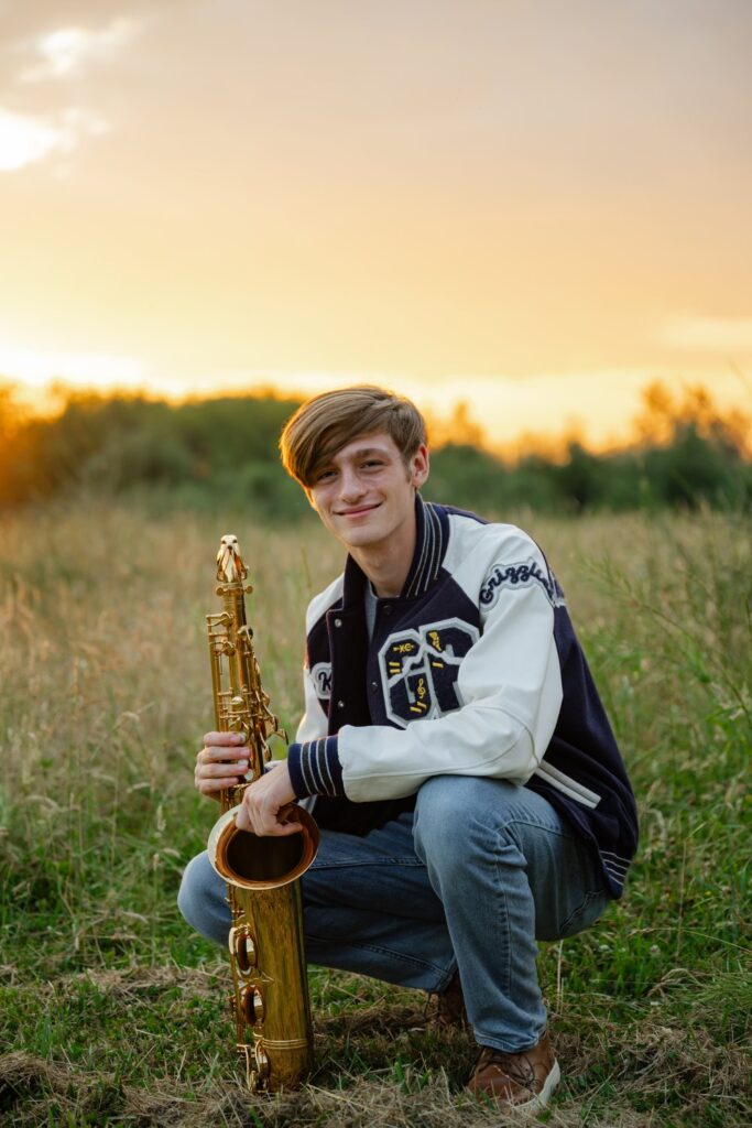 senior guy in field with saxaphone and letterman jacket