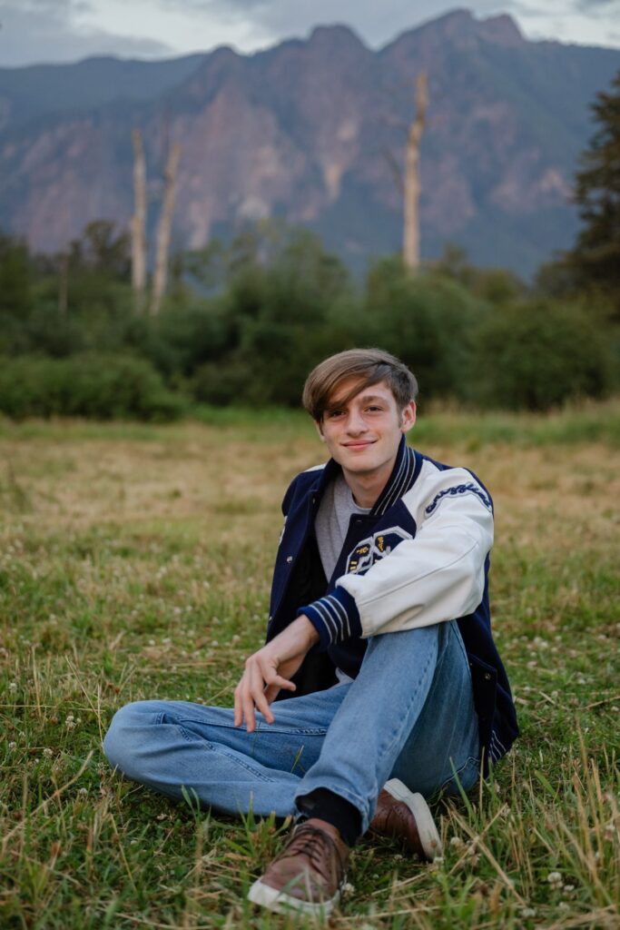 high school senior guy at meadowbrook farm north bend sitting on grass field