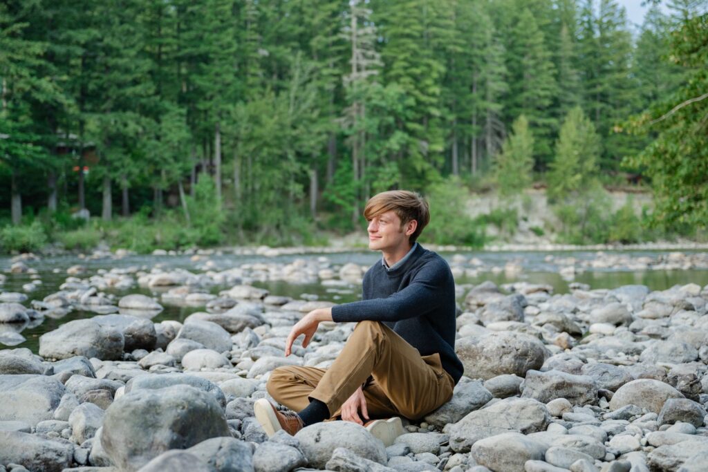senior boy at tanner landing river park sitting on rocks
