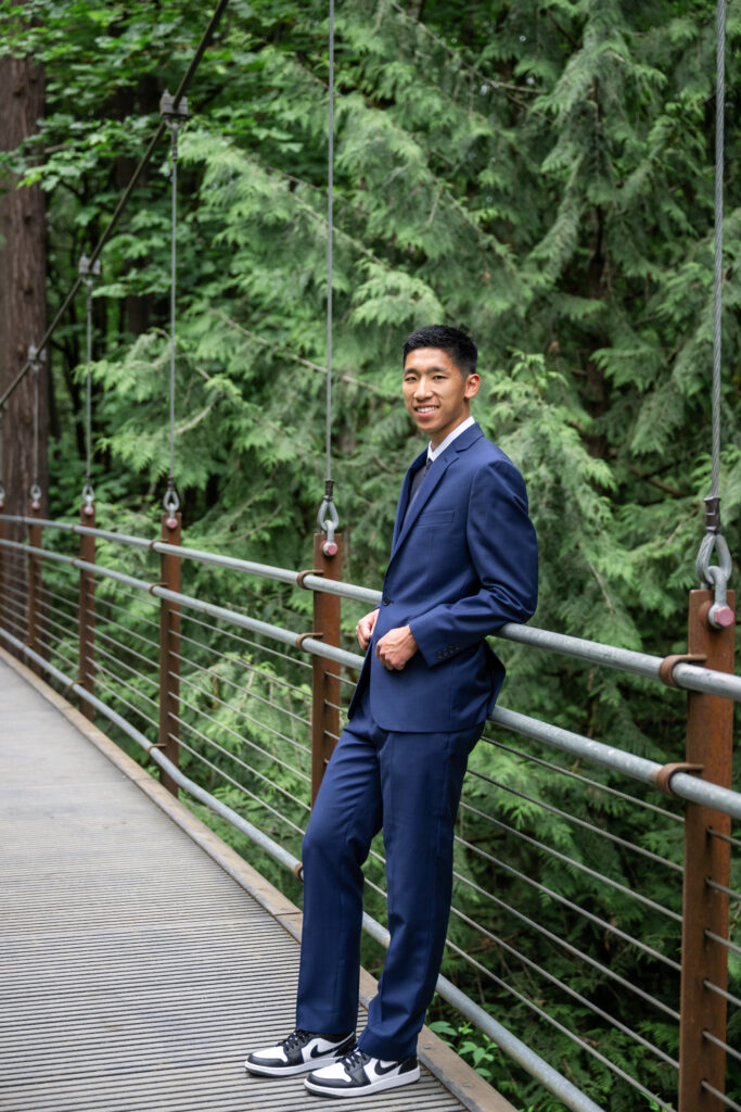 high school senior in blue suit at bellevue botanical garden suspension bridge