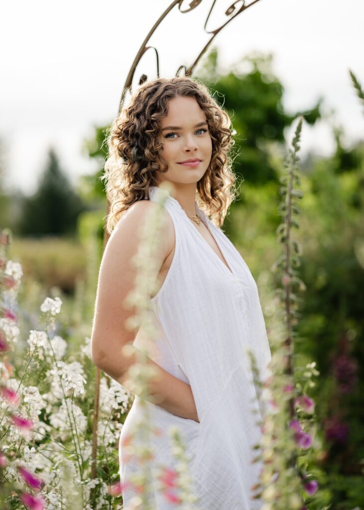 senior girl poses in white dress at flower garden in snohomish