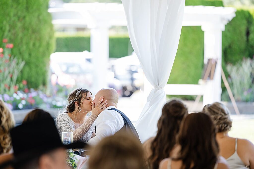 bride and groom kiss under reception tent at nature's connection
